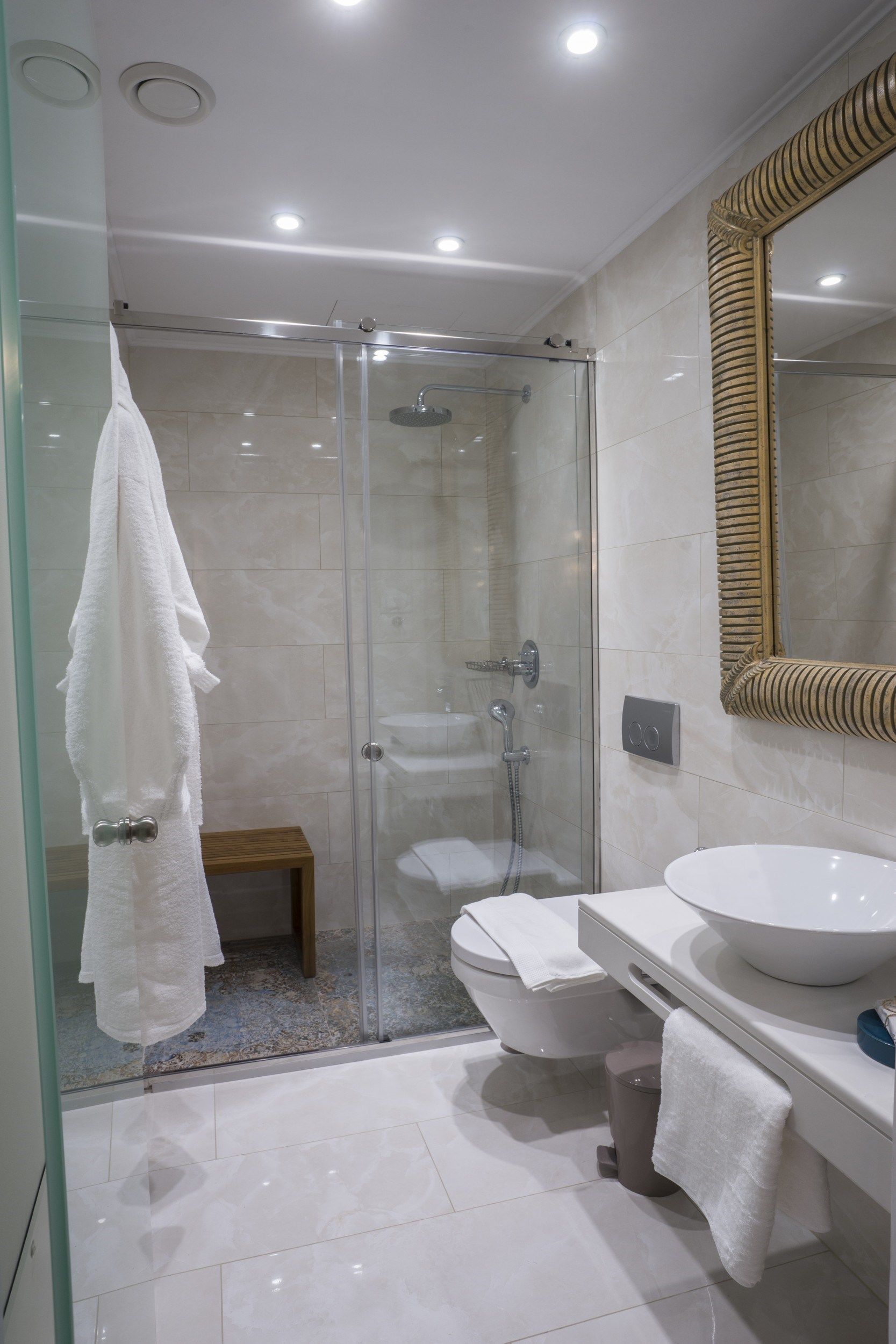 Une salle de bain moderne avec une douche à parois de verre, un lavabo blanc et un grand miroir.