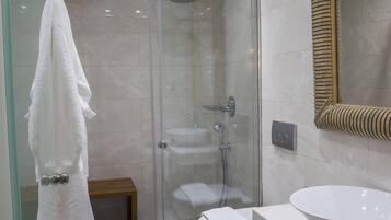 Une salle de bain moderne avec une douche à parois de verre, un lavabo blanc et un grand miroir.