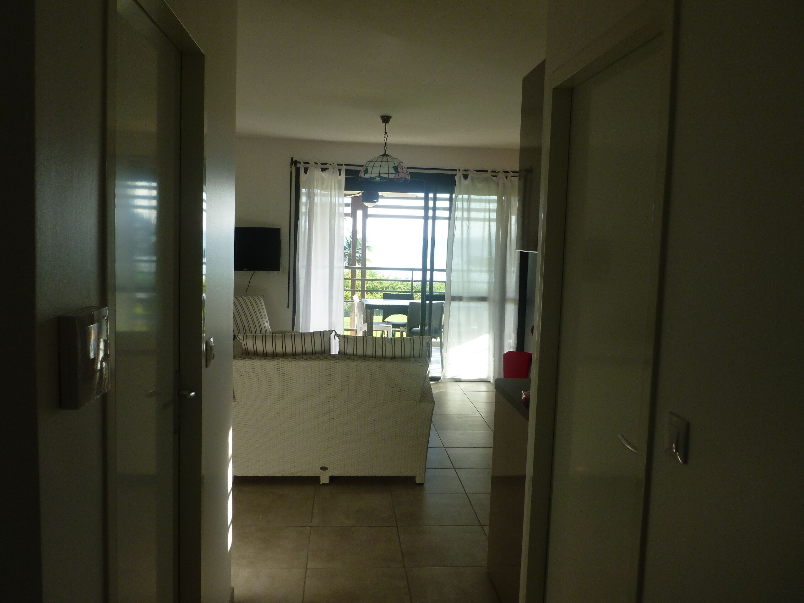 Ein Hotelzimmer mit Bett, Fernseher, einem Fenster mit Vorhängen und Blick ins Freie.