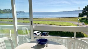 Un balcon avec une table, des chaises, un bol bleu et une assiette en forme de poisson.