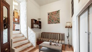 Un salon avec un escalier en bois, un canapé, une table basse et une lampe fixée au mur.