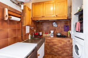 Une cuisine compacte avec des meubles en bois, un lave-linge, une machine à café et un four à micro-ondes.