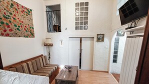 Une pièce avec un canapé, une table en bois, un téléviseur et une porte.
