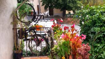 A courtyard with a tiled floor, a bicycle, and various potted plants and flowers.