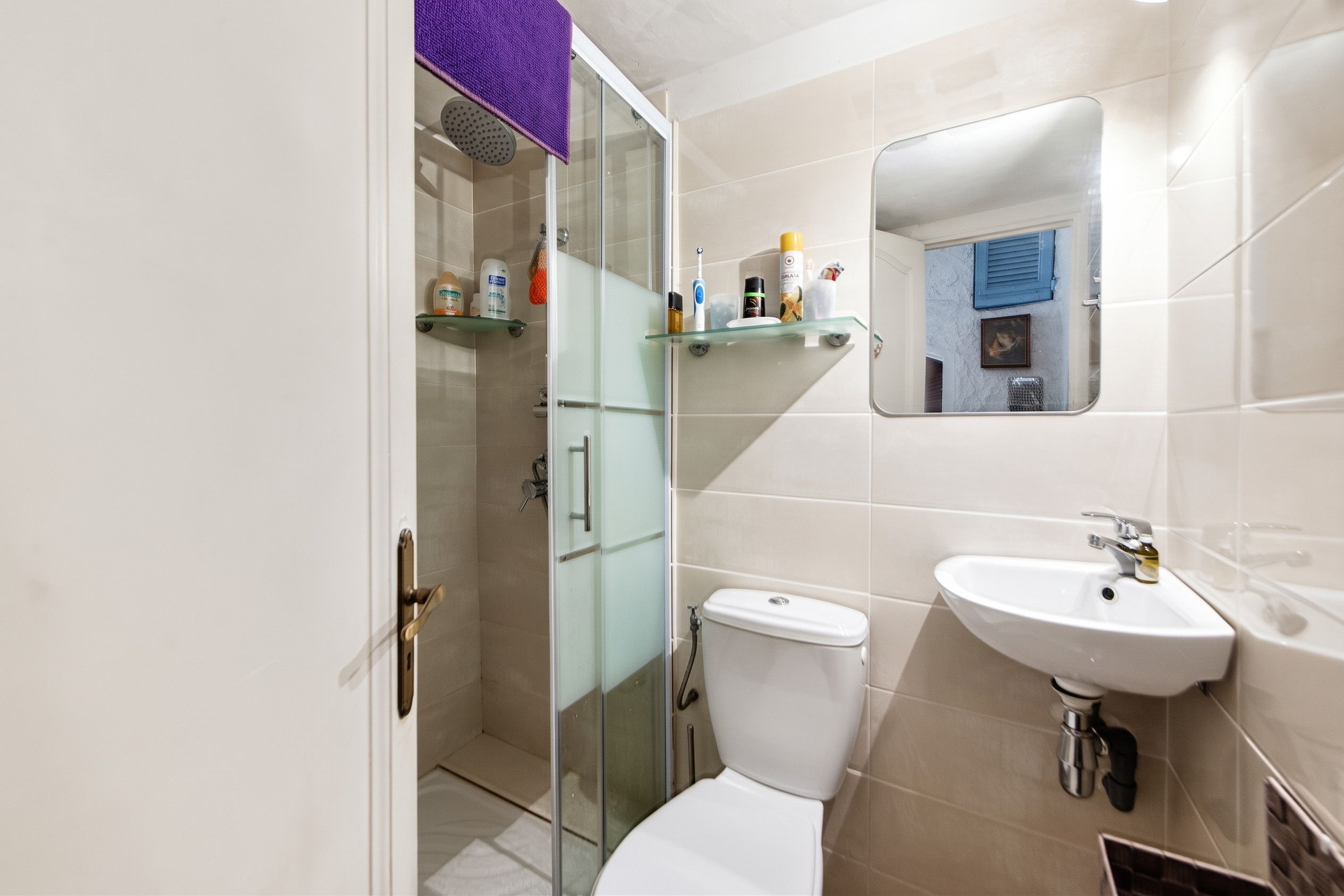 Un baño con cabina de ducha de vidrio, inodoro, lavabo y espejo.