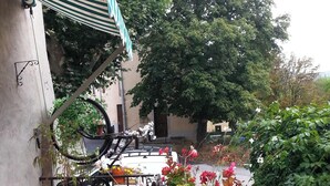 Un espace extérieur abrité, doté d’un sol carrelé, d’un support à vélos et de divers pots de plantes et de fleurs.
