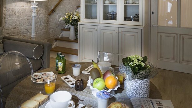 A breakfast setup with a table, breakfast items, a cabinet, and a lamp. - B&B C'era una volta (Alberobello)
