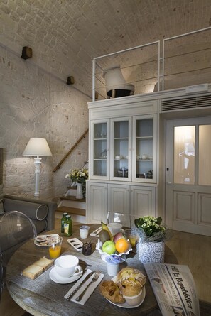 A breakfast setup with a table, breakfast items, a cabinet, and a lamp.