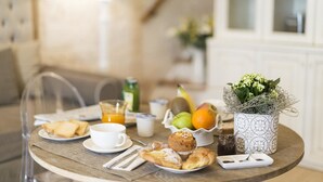 A breakfast setting with pastries, fruits, and a decorative vase on a wooden table. - B&B C'era una volta (Alberobello)