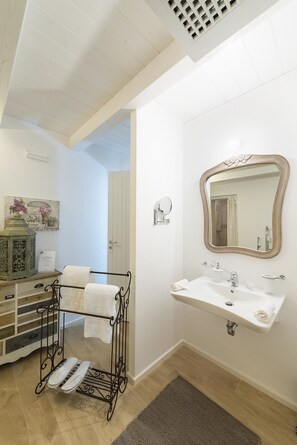 A bathroom with a white sink, a mirror, and a towel rack.