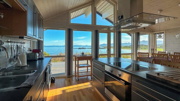 Una cocina moderna con amplios ventanales que ofrecen una vista panorámica del mar y las montañas.
