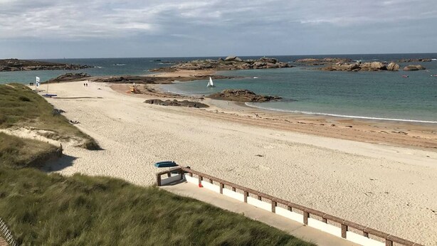 A beach with a sandy shore, a wooden walkway, and rocky outcrops in the water. - Modern Single-Level House with WiFi, Terrace, and Parking in Trégastel (Trégastel)