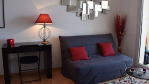 A modern living room with a grey sofa, red cushions, a small table with candles, a lamp, and a decorative mirror wall. - Apartment with WIFI, Beachfront, Private Parking, Pets Allowed (Trégastel)