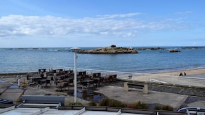A coastal area with outdoor seating overlooking the sea, a rocky island in the distance, and a clear sky. - Apartment with WIFI, Beachfront, Private Parking, Pets Allowed (Trégastel)