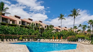 Ein Poolbereich eines Resorts mit klarem, blauem Wasser, Liegestühlen und Palmen.
