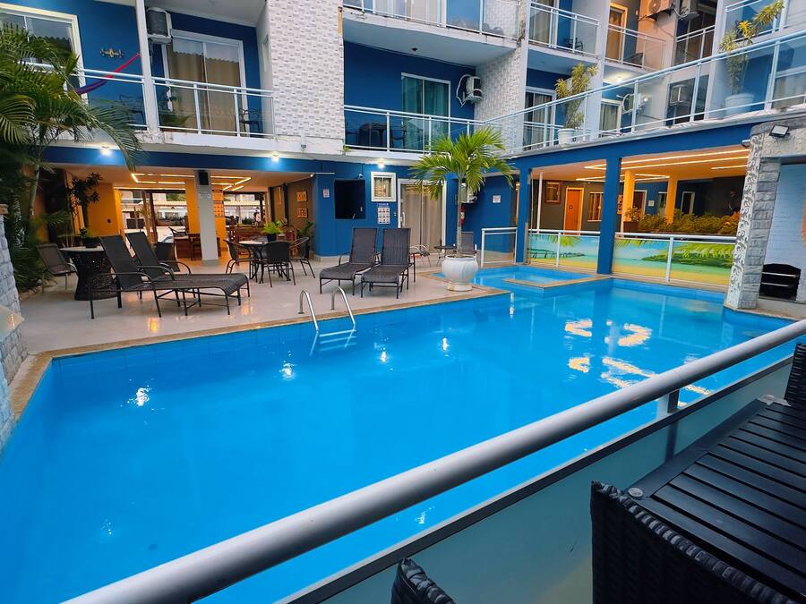 A hotel with a swimming pool, lounge chairs, and a dining area.