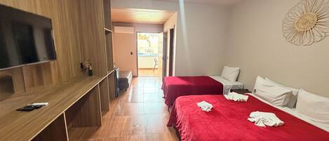 Une chambre d’hôtel avec deux lits, une télévision, un bureau et une vue sur l’extérieur.