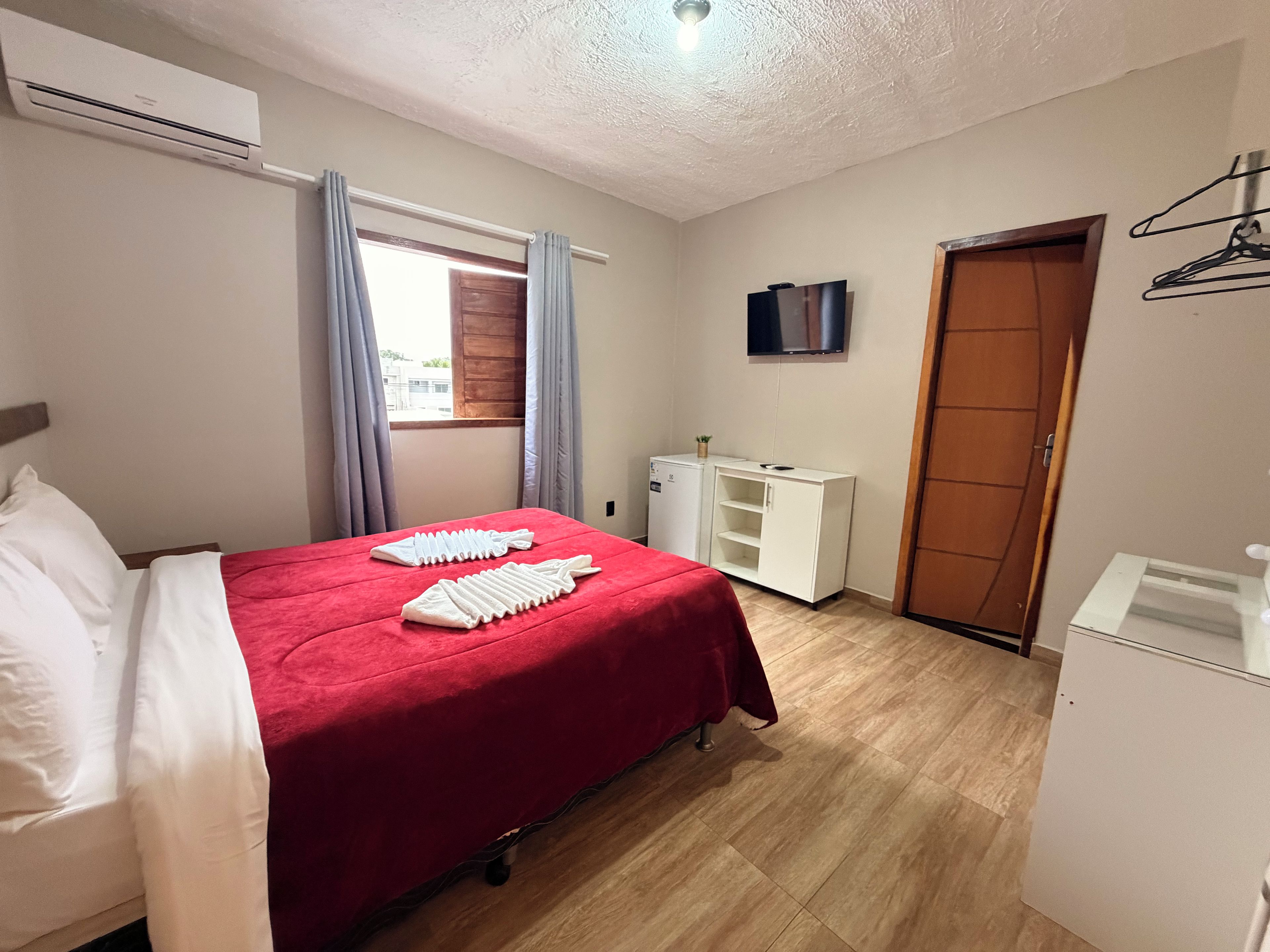 A hotel room with a bed, a wardrobe, a small desk, and a television.