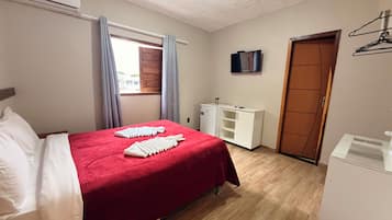 A hotel room with a bed, a wardrobe, a small desk, and a television.