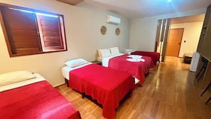 Quarto de hotel com duas camas de solteiro, um sofá, uma mesa pequena e uma televisão.