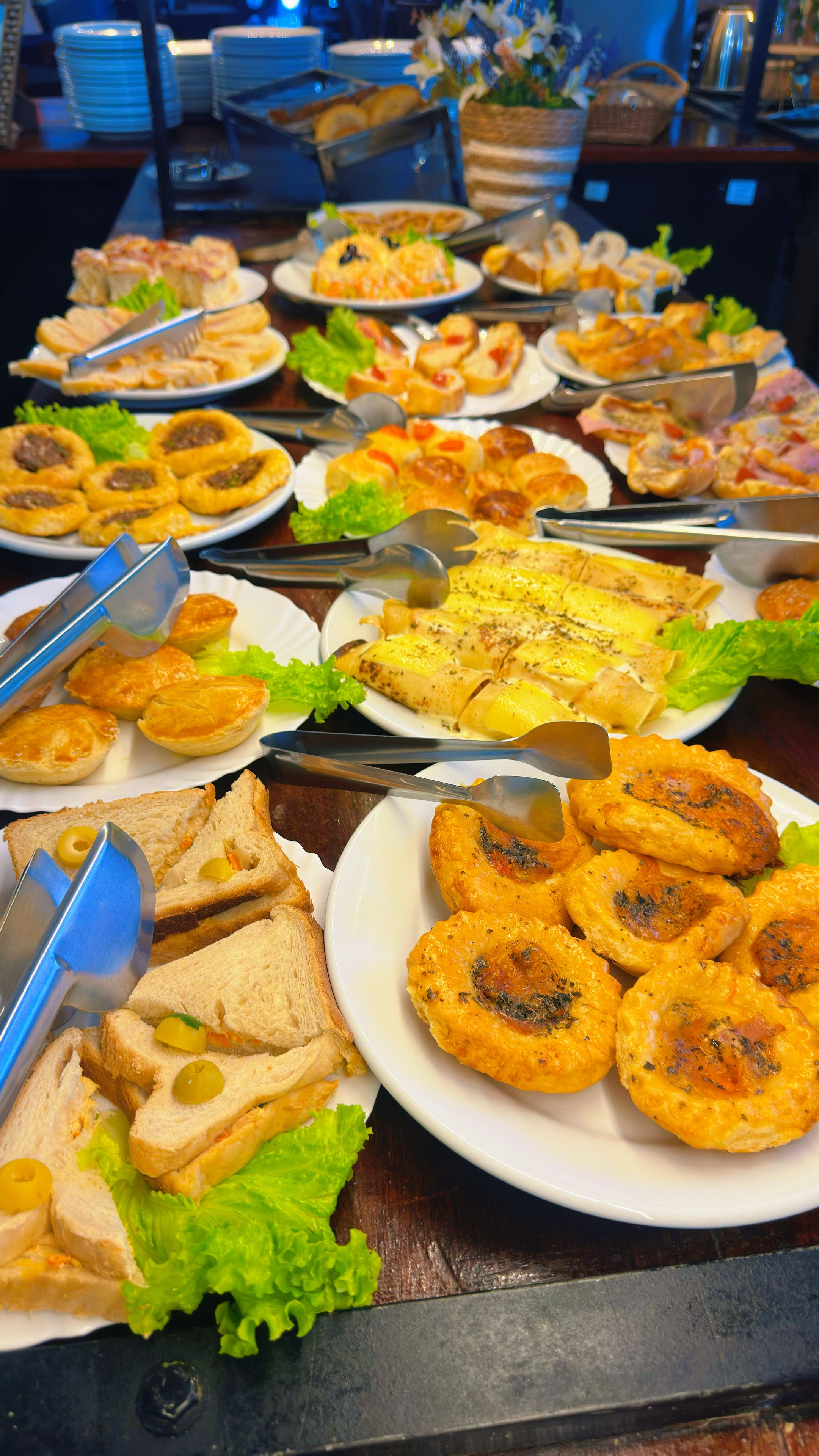 Een buffet met diverse gerechten, waaronder belegde broodjes, salades en gebak.