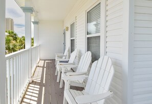 A covered porch with white wooden chairs and a railing. - 3-Story Beach Cottage in Miramar Beach w/ 2 Wrap Around Balconies! 🌴💙 (Miramar Beach)