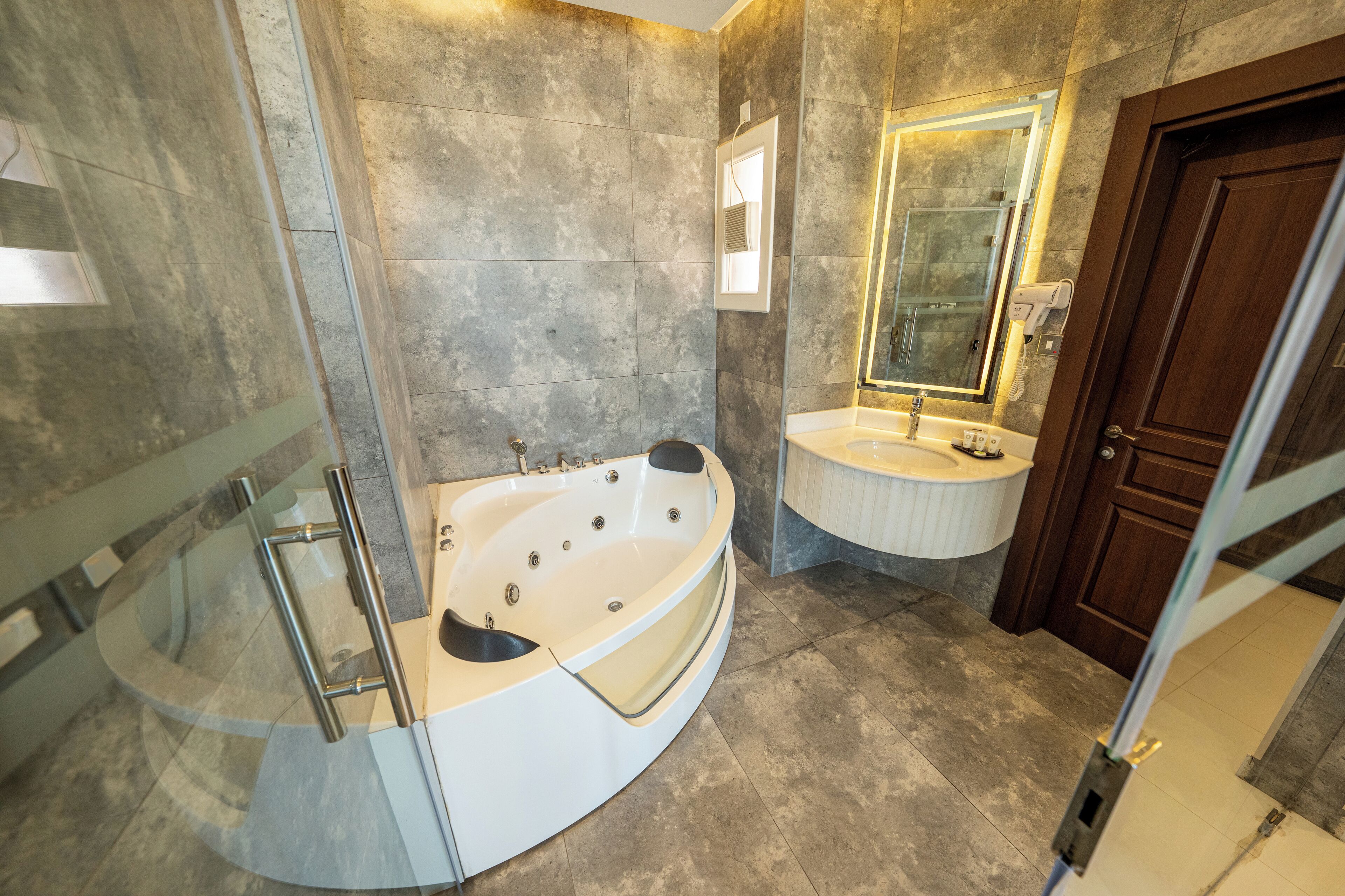 Un baño moderno con una bañera independiente, un tocador con lavabo y un espejo grande.