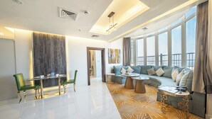 Ein modernes Wohnzimmer mit Sofa, Couchtisch und Sesseln, großen Fenstern mit Blick und einem gemusterten Teppich.