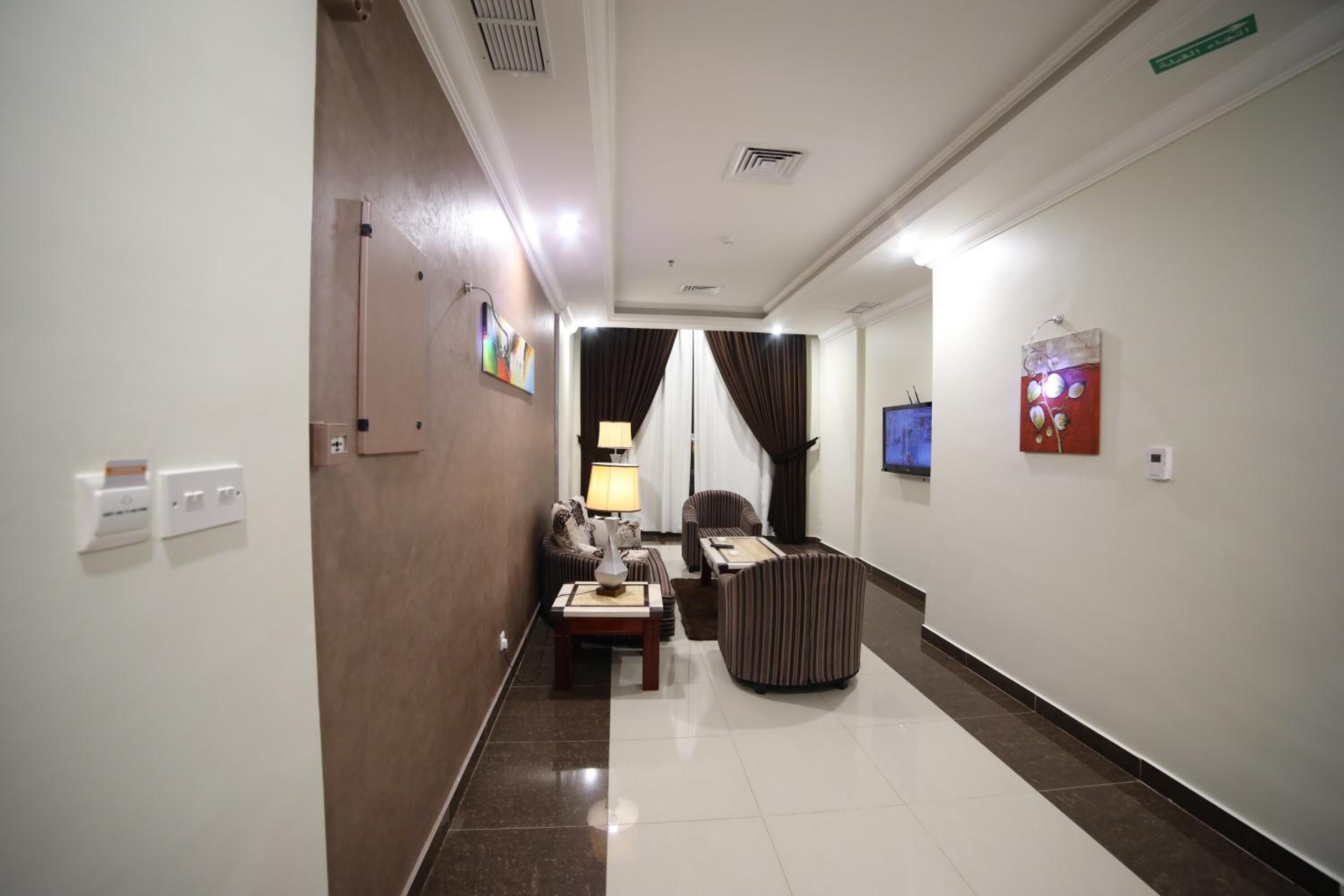 A hotel hallway with a sofa set, a lamp, and a TV mounted on the wall.