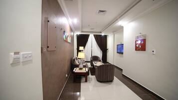 A hotel hallway with a sofa set, a lamp, and a TV mounted on the wall.