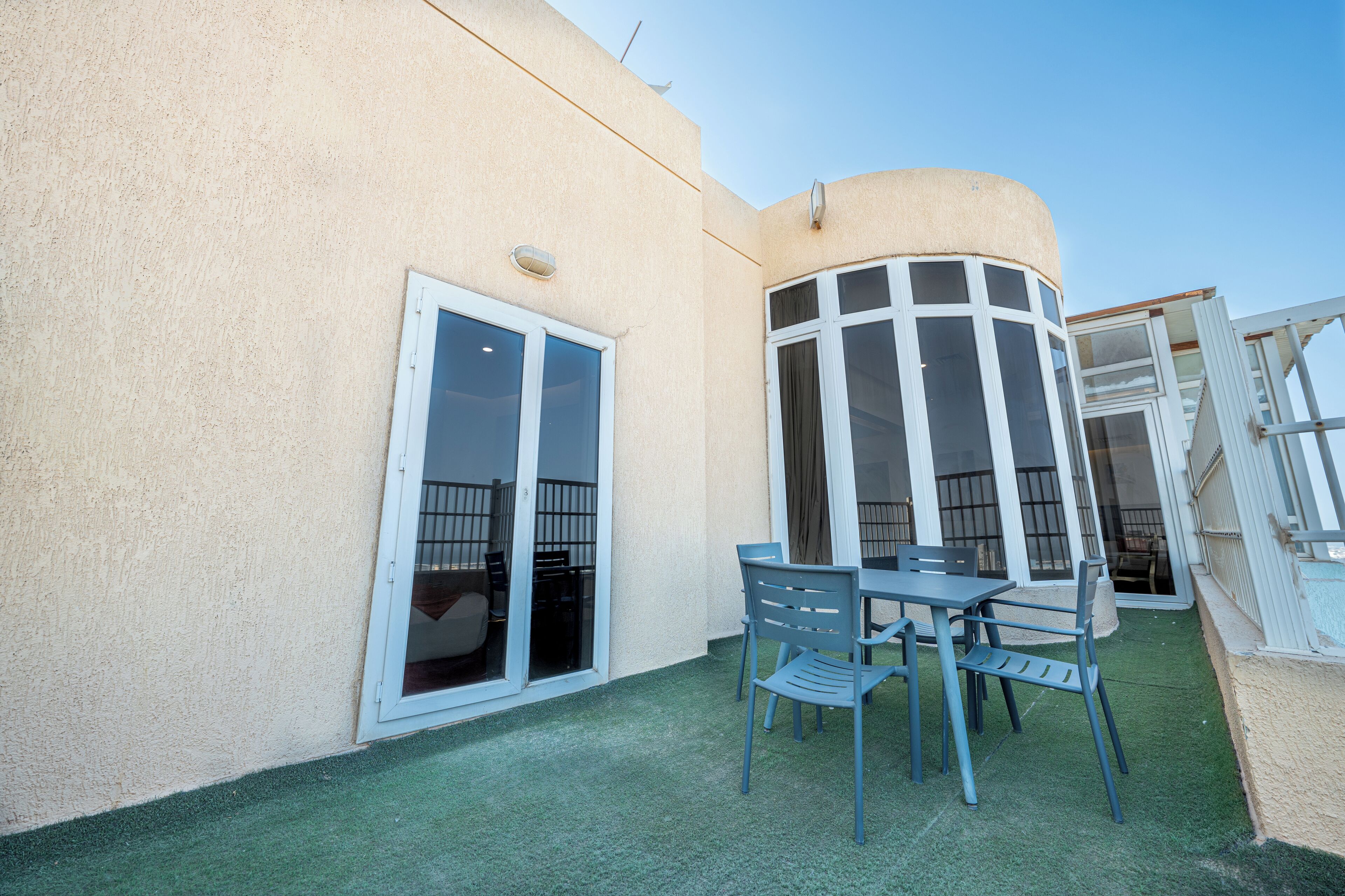 A patio area with a table and chairs, a sliding glass door, and a curved window.