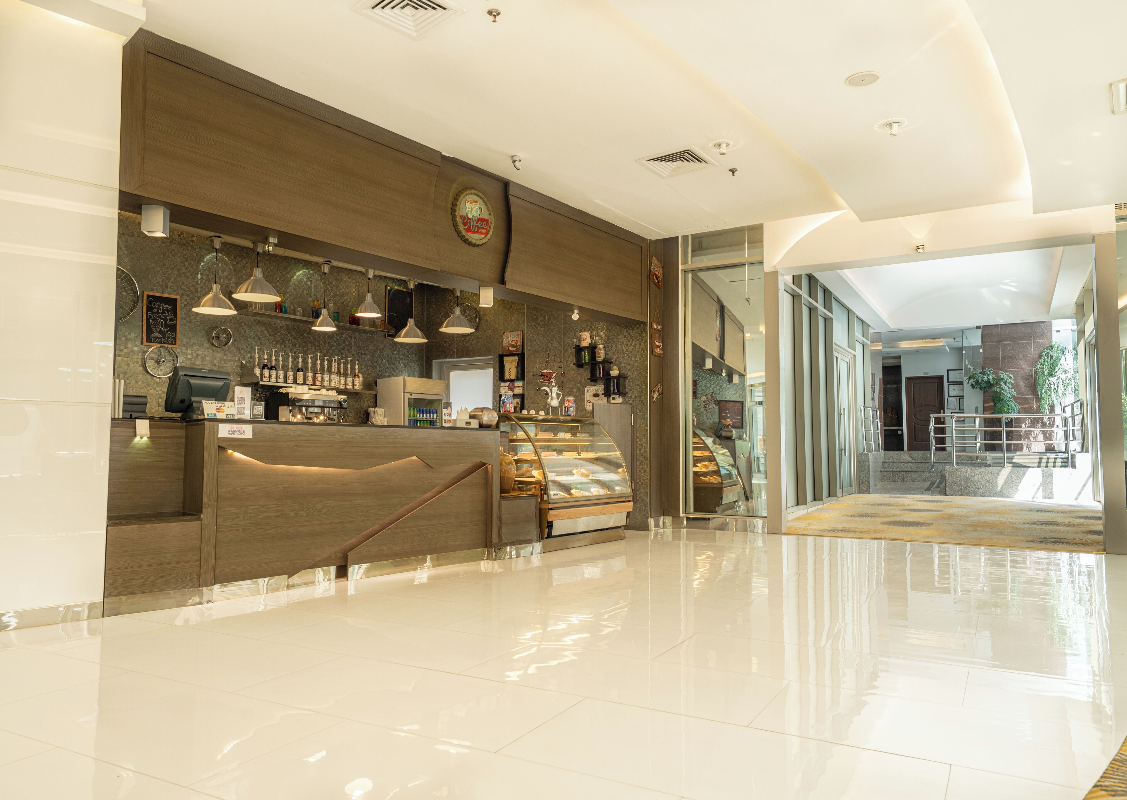 A modern coffee shop with a wooden counter, espresso machines, and a display case with pastries.