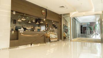 A modern coffee shop with a wooden counter, espresso machines, and a display case with pastries.