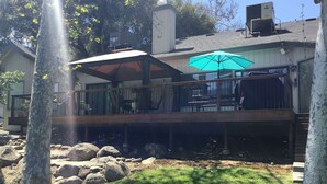 Een huis met een terras, een overdekte patio en een grote parasol.