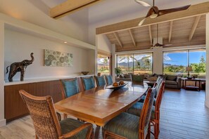 A spacious dining area with a wooden table and chairs, a ceiling fan, and a view of the outdoors.