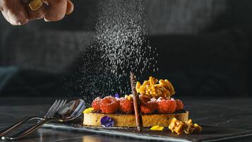 Dessert mit Himbeeren, Nüssen und einem Schokoladendecke auf einem Teller.