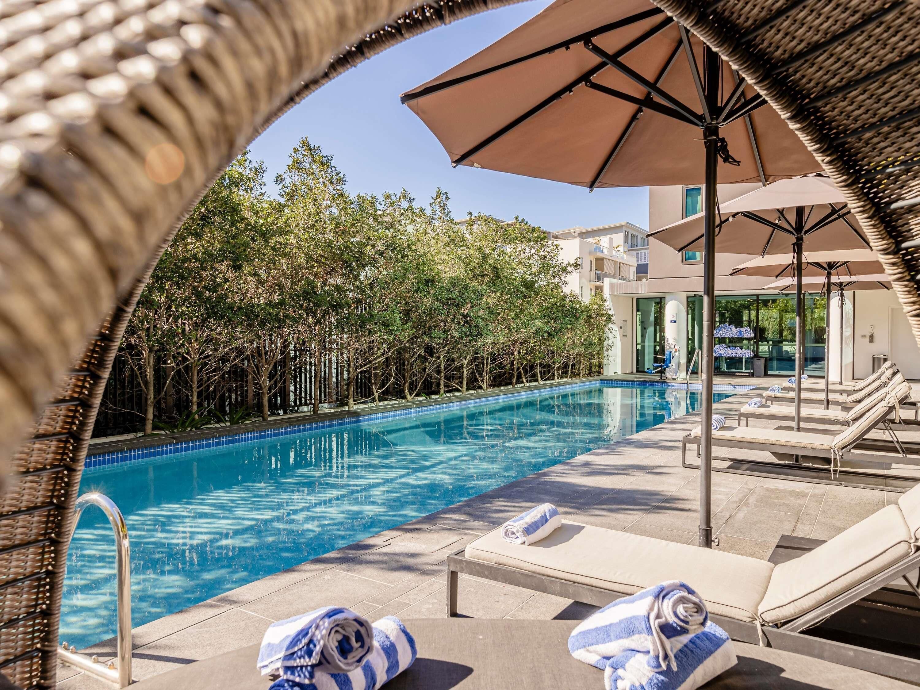 Una piscina al aire libre, sillones reclinables de piscina