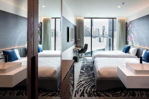 A modern hotel room with two beds, a desk, and a large window offering a city view. - Novotel Brisbane South Bank Hotel (South Brisbane)