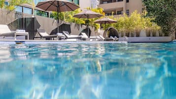 Una piscina al aire libre, sillones reclinables de piscina