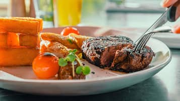 A plate with steak, fries, and a cherry tomato.