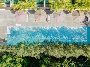 An aerial view of a swimming pool with clear blue water, surrounded by palm trees and umbrellas. - Novotel Brisbane South Bank Hotel (South Brisbane)