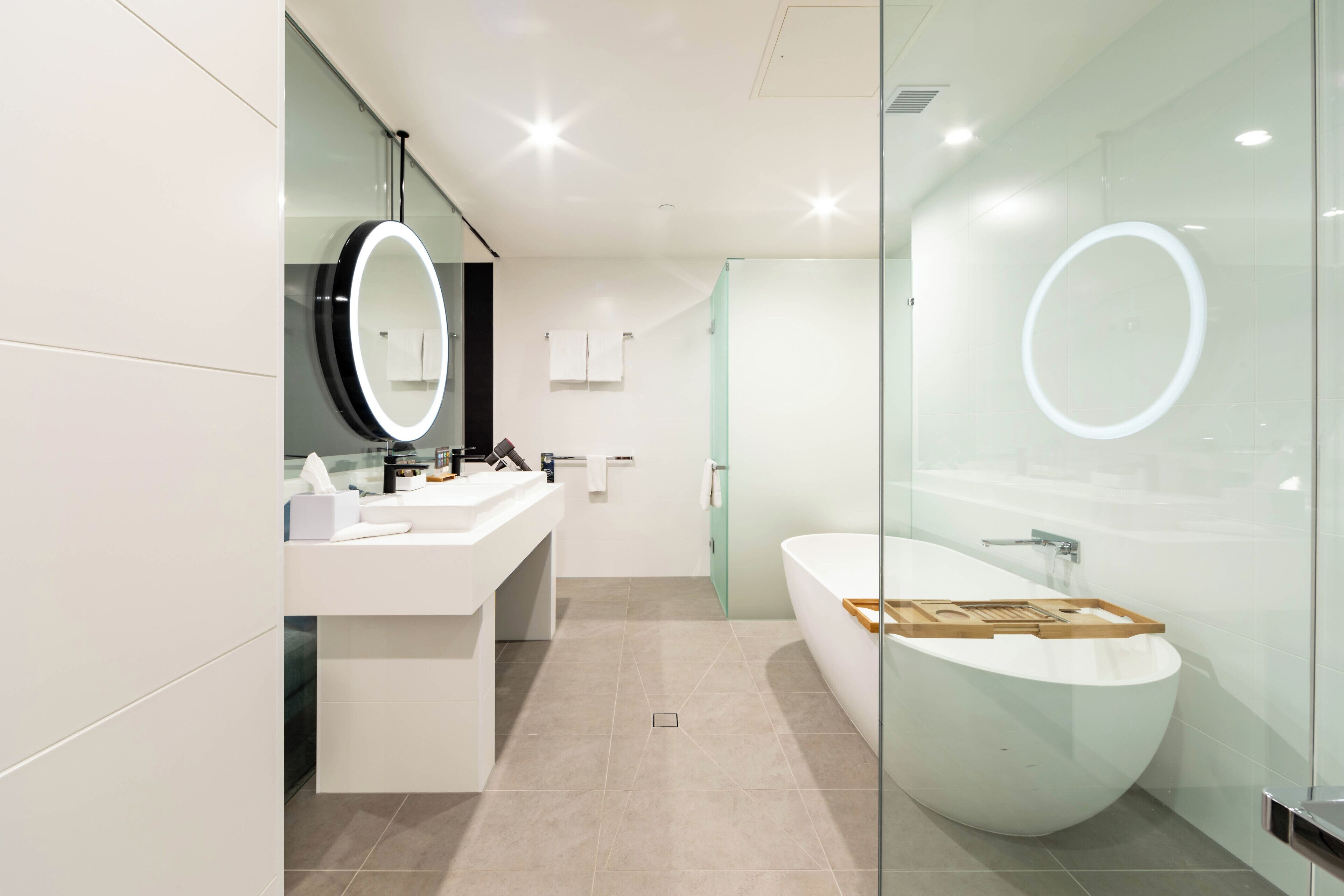 Ein modernes Badezimmer mit einer großen, ovalen Badewanne, einem Waschtisch mit Spiegel und einer separaten Duschkabine.