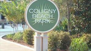 Un panneau indiquant l’entrée du parc de Coligny Beach, avec une forme circulaire et une petite structure couverte au sommet.