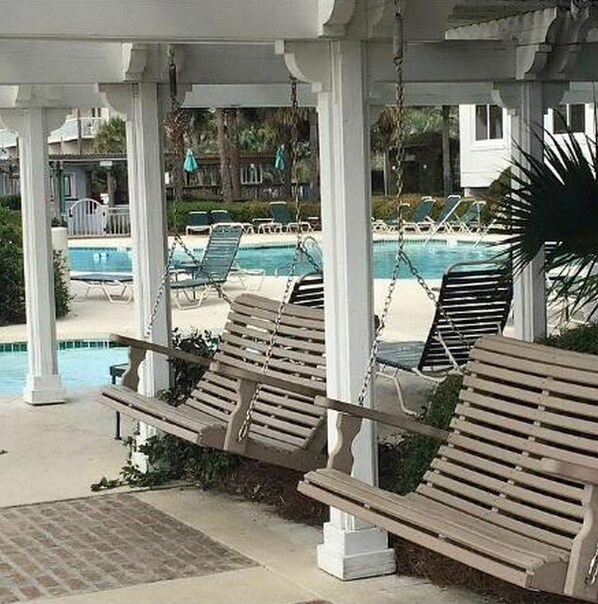 Relax in style by the serene pool, surrounded by lounge chairs and white columns.