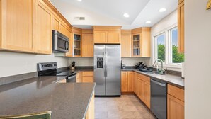 A modern kitchen with wooden cabinets, stainless steel appliances, and a large window providing natural light.