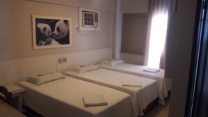 A hotel room with two single beds, a small window, and a framed picture on the wall. - Hotel Gramado de Campos (Campos)