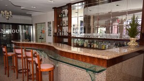 A bar area with a curved granite countertop, wooden bar stools, and a mirrored wall. - Hotel Gramado de Campos (Campos)