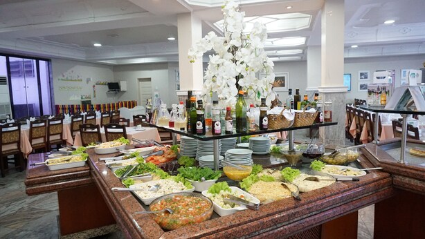 A buffet area with various food stations, a selection of beverages, and a decorative white orchid arrangement. - Hotel Gramado de Campos (Campos)