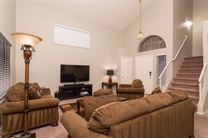 A living room with a flat-screen TV, two sofas, a coffee table, a lamp, and a staircase. - Arrowhead Area, Quiet, Comfy, 4 TVs (Peoria)