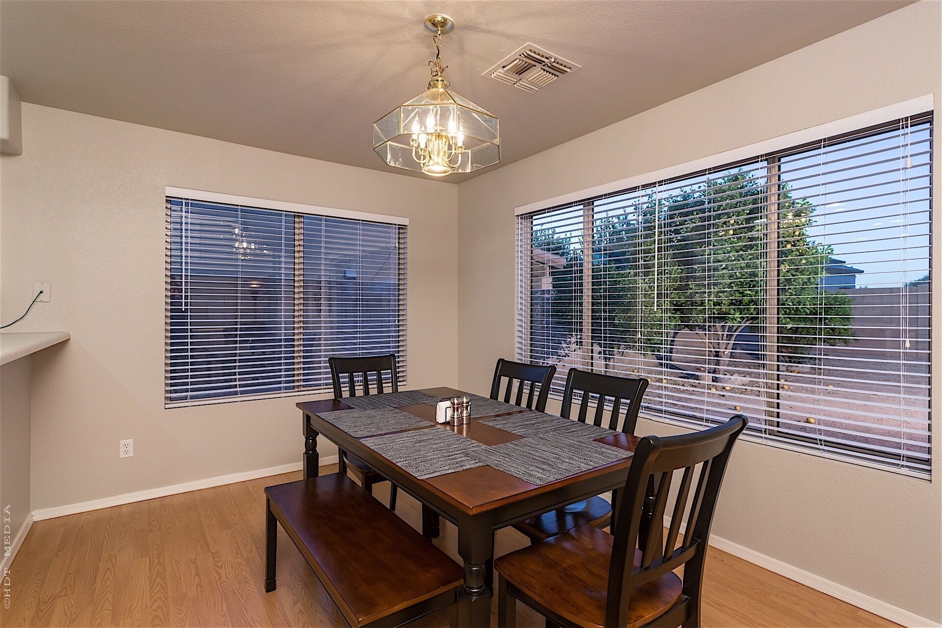 A dining area with a wooden table, four chairs, and a chandelier.